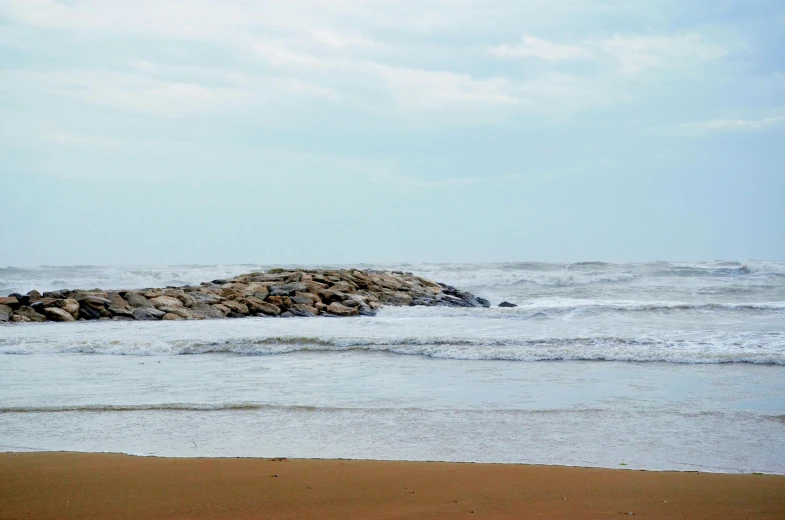 a sandy beach covered in rocks with water