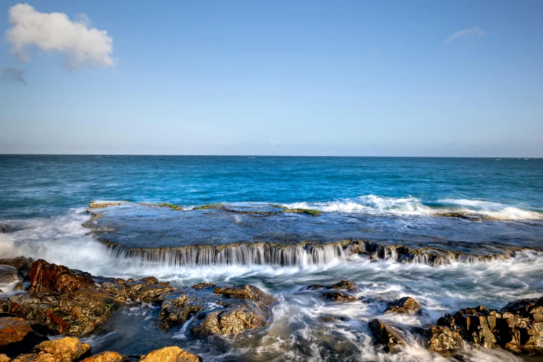 the ocean with the rocky shore covered in waves