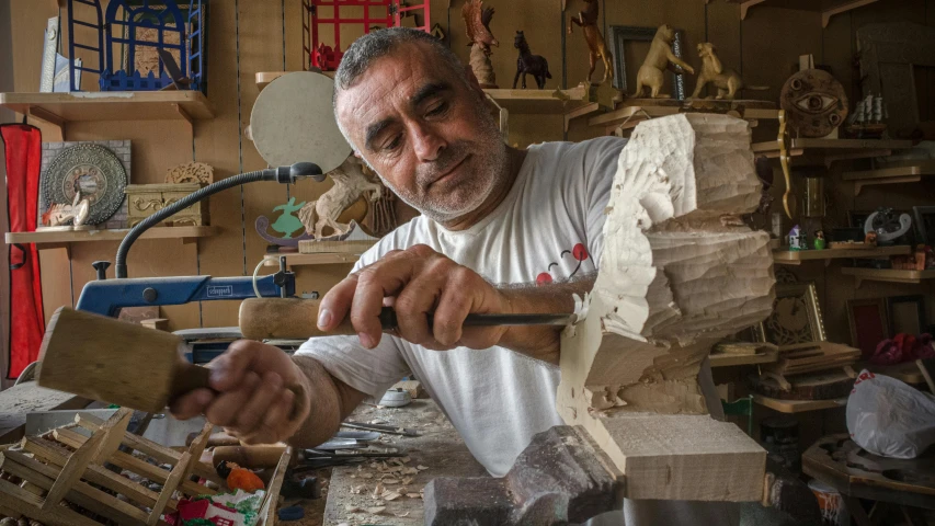 man working with wooden carving supplies in his work bench