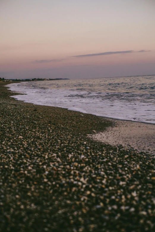 two people are standing on the beach, looking out over water