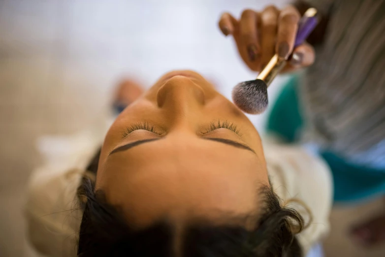 a woman is using a brush on her eye