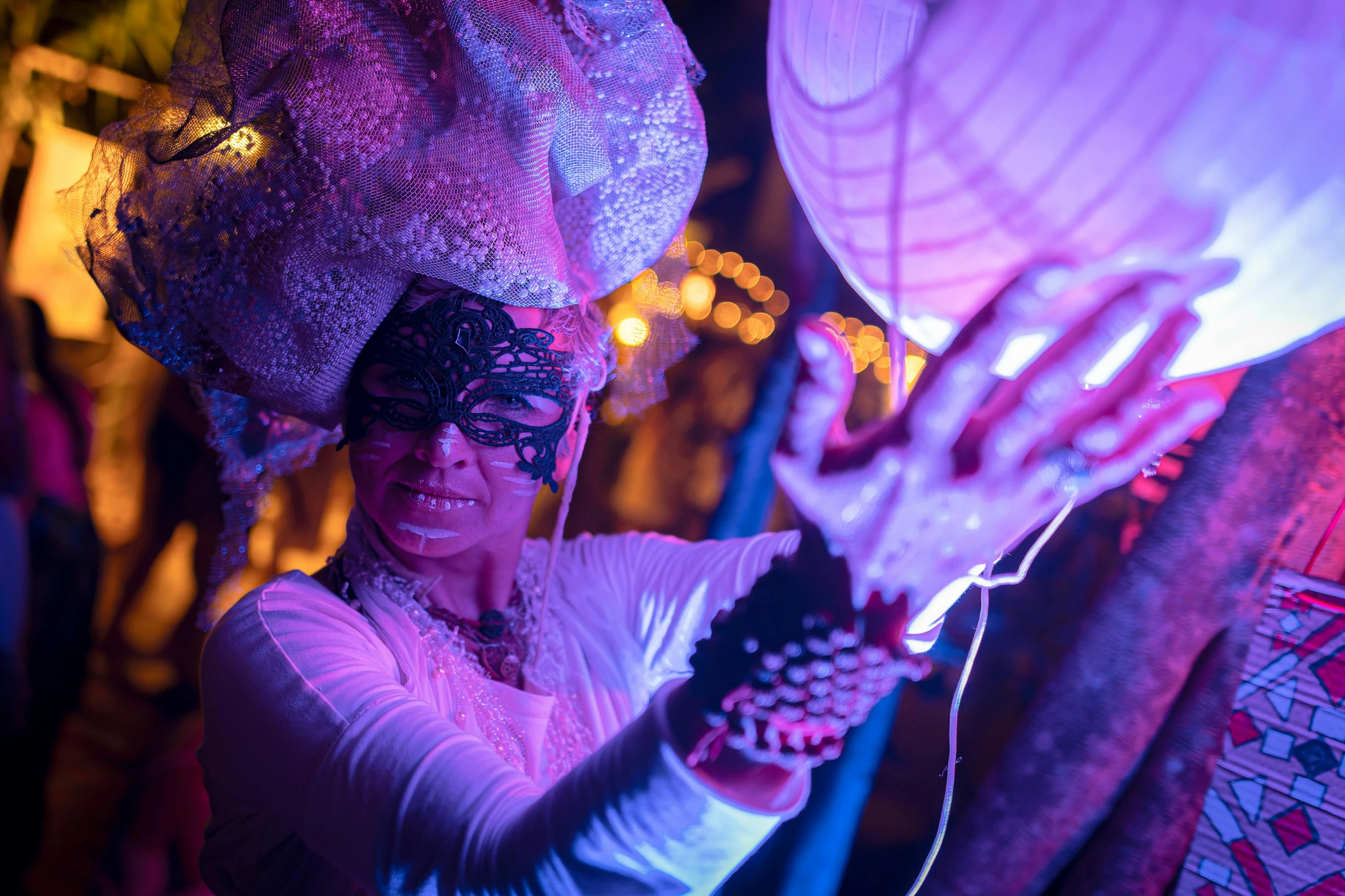 a woman holds up paper lantern at night