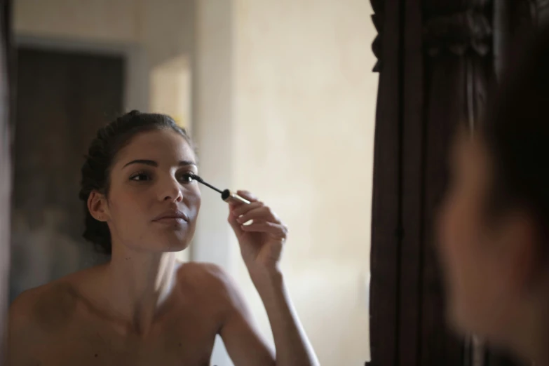 a woman brushes her teeth in a mirror