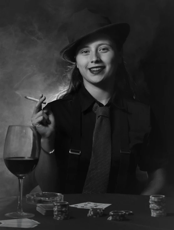 a woman smoking while sitting at a table with wine glass