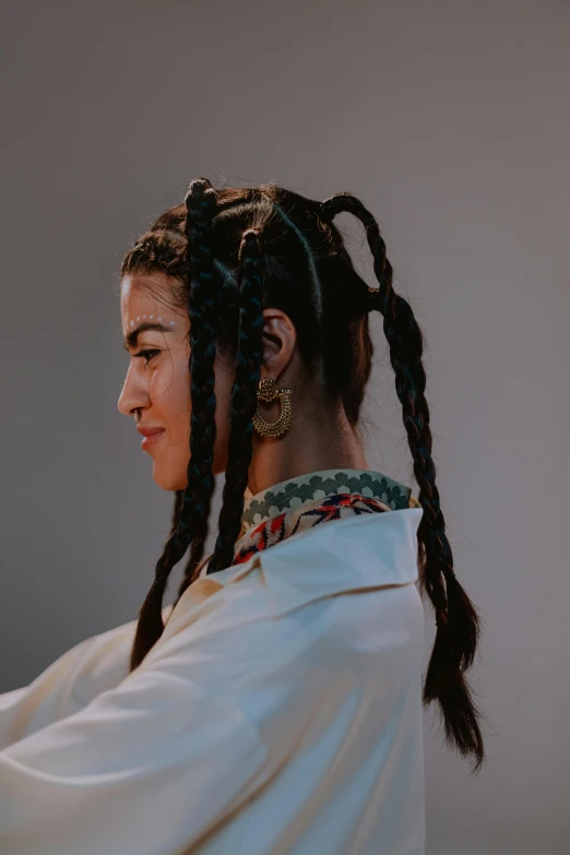 a woman with large earrings wearing a white shirt and long hair