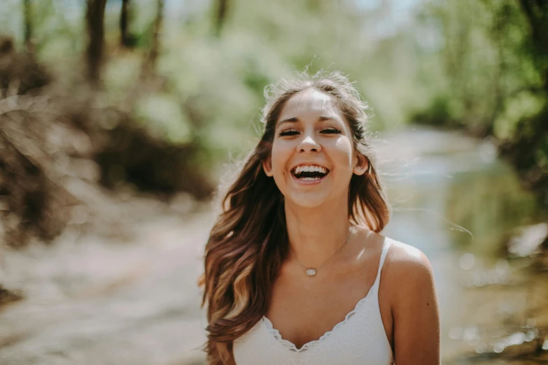 a girl standing in front of a river laughing