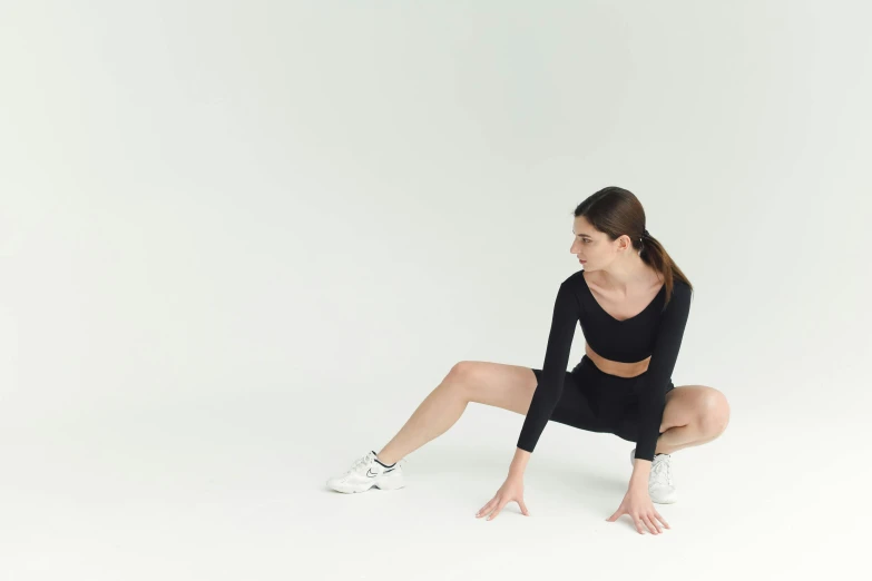 a woman in black crouching down on her feet