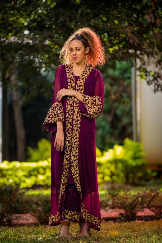 woman in dress standing near trees in sunny area