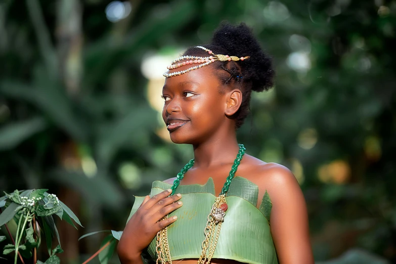 an african american woman wearing green and gold in front of trees