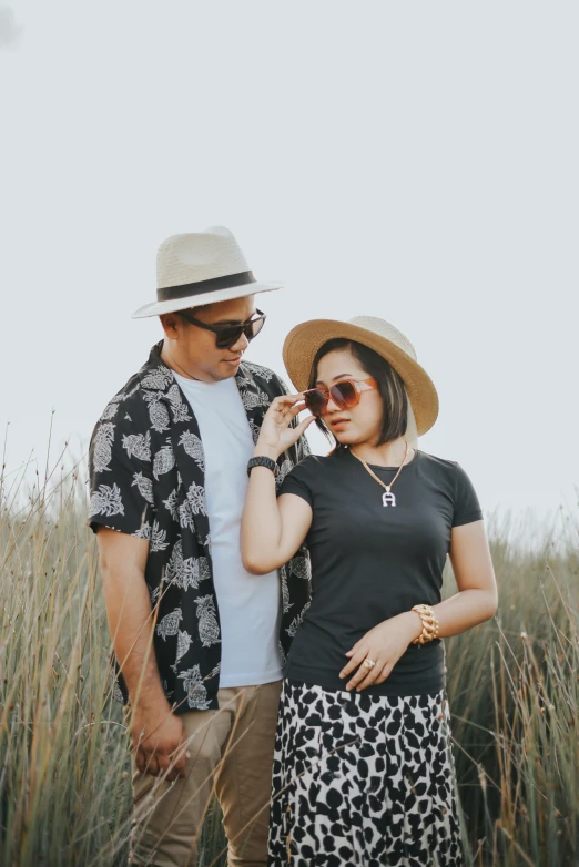 a couple with sun glasses talking in a field