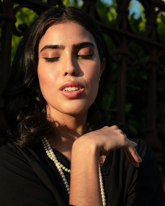 a woman with a black shirt and pearls is wearing a necklace