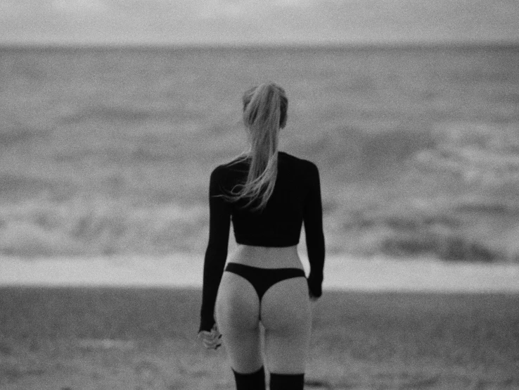 woman on beach in black and white outfit walking away from ocean