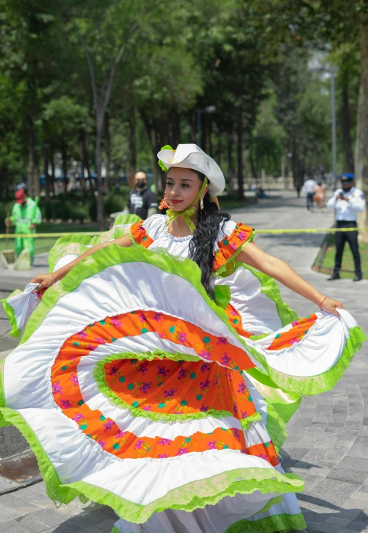 a woman wearing green, white and orange attire holds a colorfully decorated umbrella