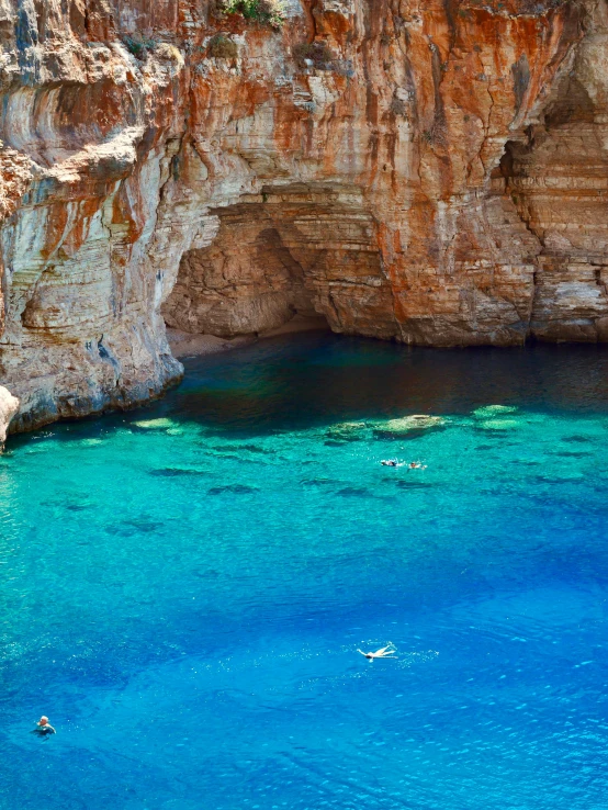 water surrounded by cliffs with people swimming