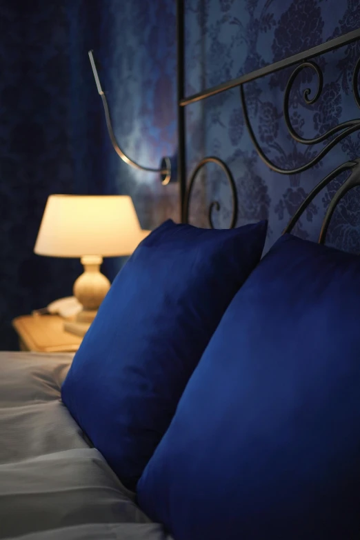 a bed with blue pillows sitting under a light