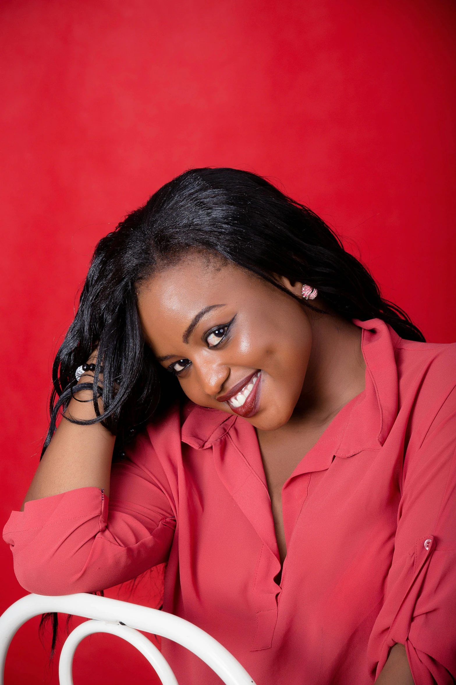 a young woman wearing a red top is smiling and holding a hairdryer