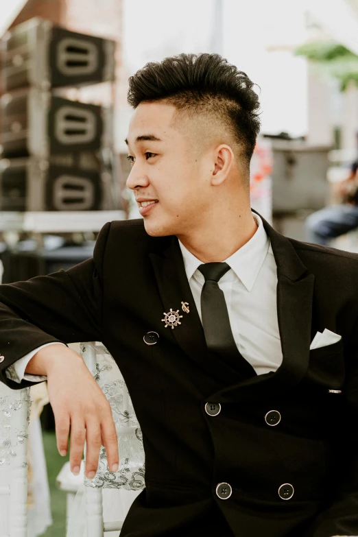 a man in a black suit and tie sitting on a bench