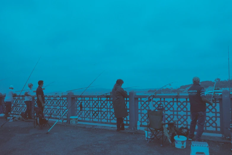 several people on a pier fishing in the ocean