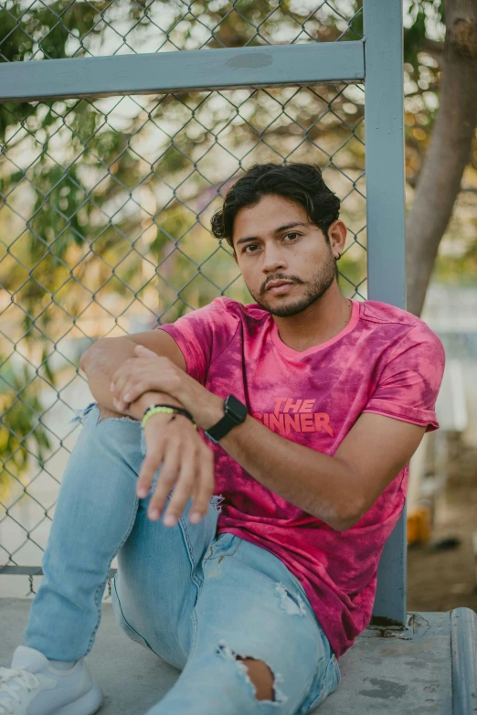 a man sitting outside wearing a watch with his hand on the ground