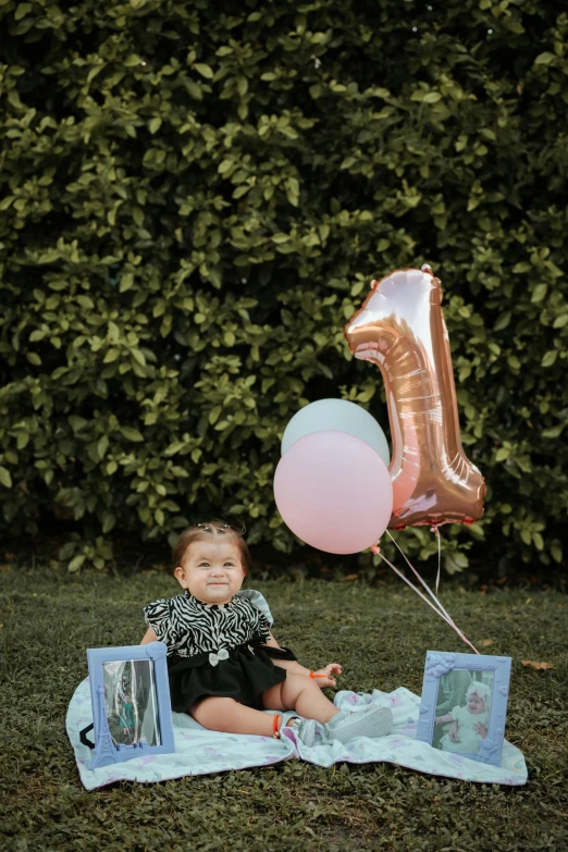 baby with pink and blue balloons at a first birthday