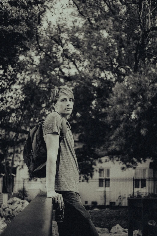 boy with hat holding a skateboard on concrete