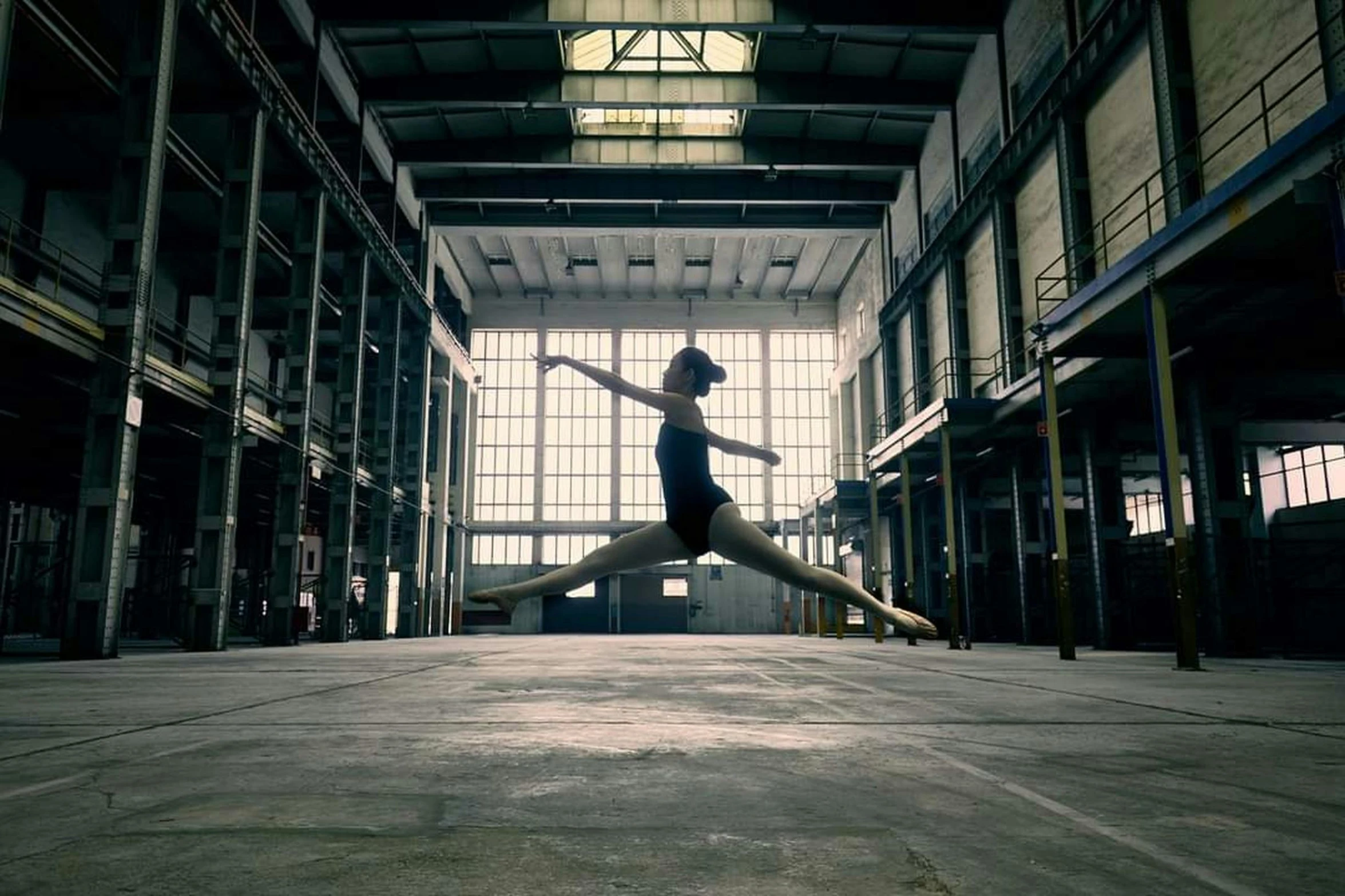 a woman stands in a warehouse with her feet up on a piece of art