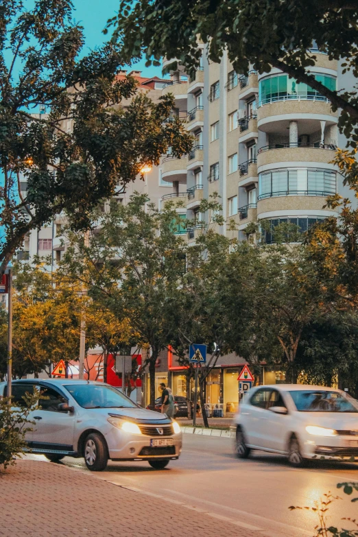 two cars are driving on the road next to an office building