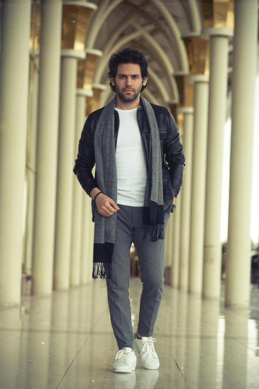 a man standing in an ornate hallway wearing all white