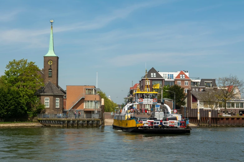 a ferry traveling past a small town on the side of a river