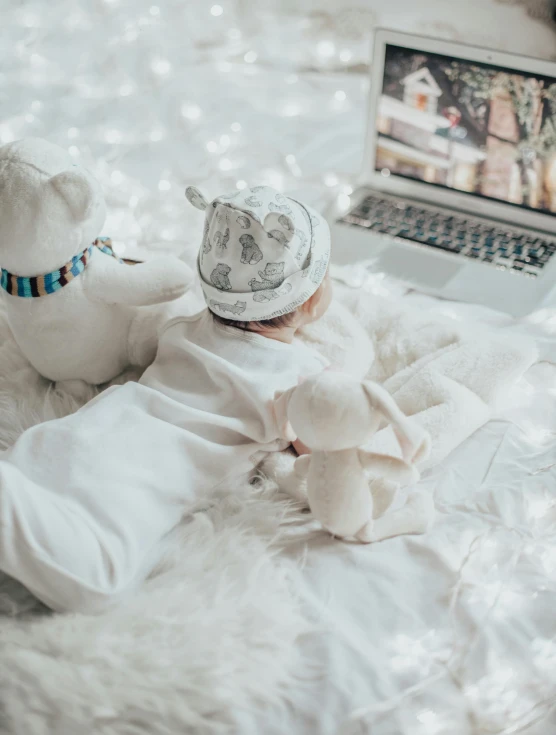 a small child wearing a hat looking at a laptop