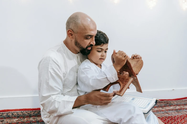 a man is holding a child who is reading a book