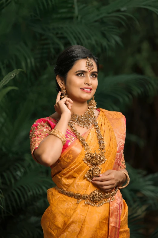 a woman wearing orange and gold holding onto her ear