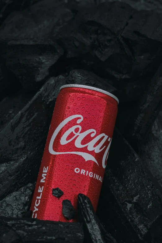 a can of coke on top of black rocks