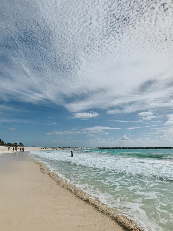 a wide beach filled with people on it next to the ocean