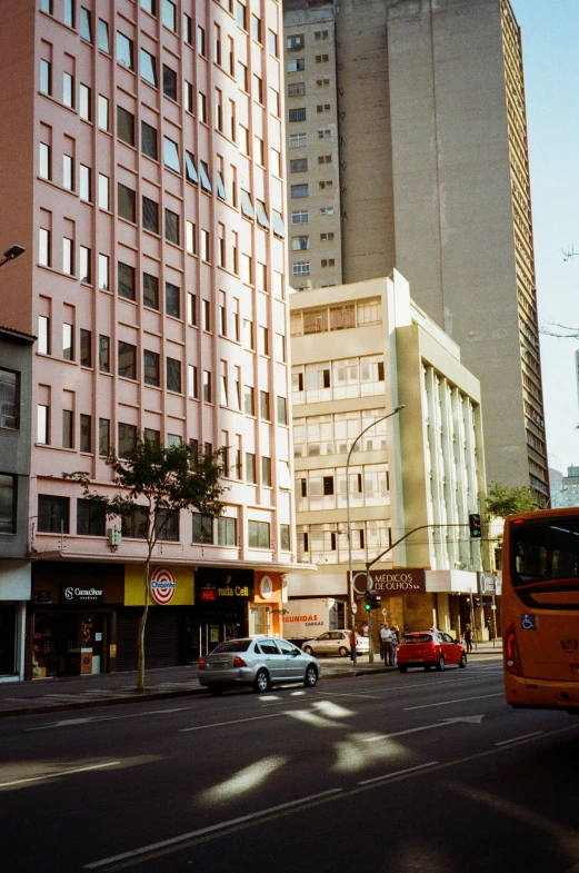 several cars sit parked on the road next to tall buildings