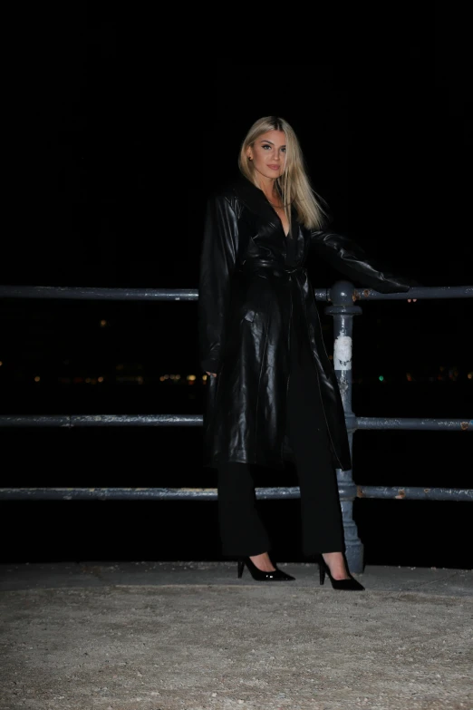 the blond woman is posing by the water at night