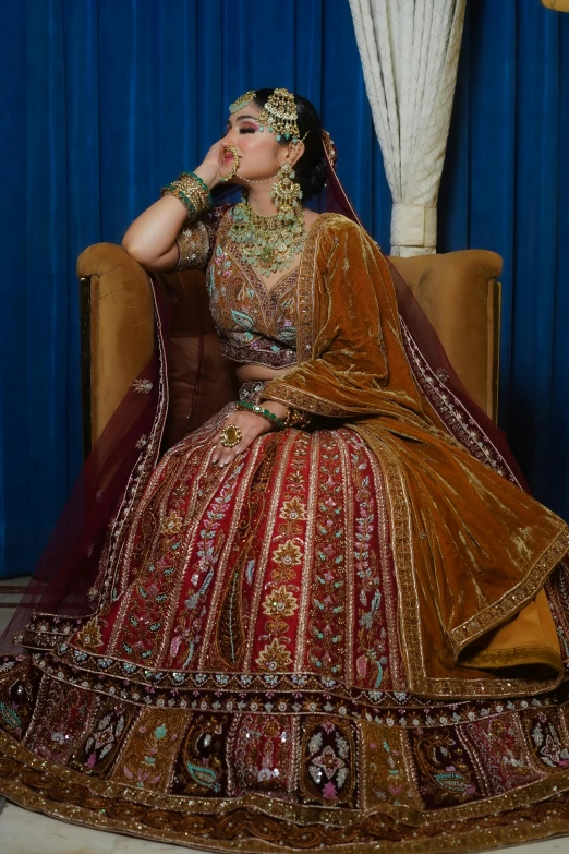 a woman dressed in indian traditional clothing sitting on a chair