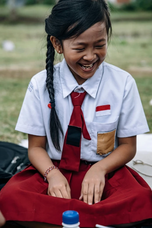 a girl smiling in the grass with her tie on