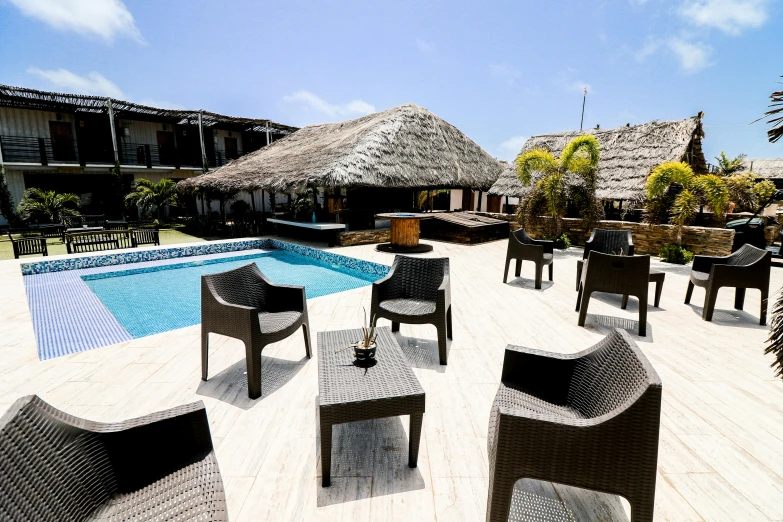 tables and chairs at the end of a patio by an outdoor pool