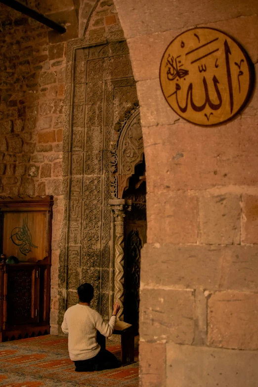 a person kneeling down while praying in an arched doorway