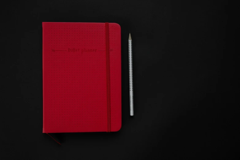 red notebook with pen on black background