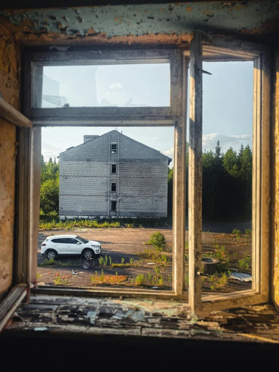 there is a window with the view of an old barn