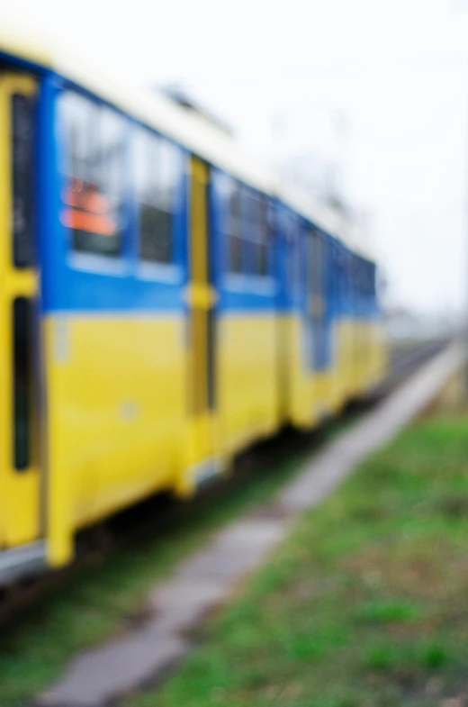 blurry image of the side of a yellow and blue train