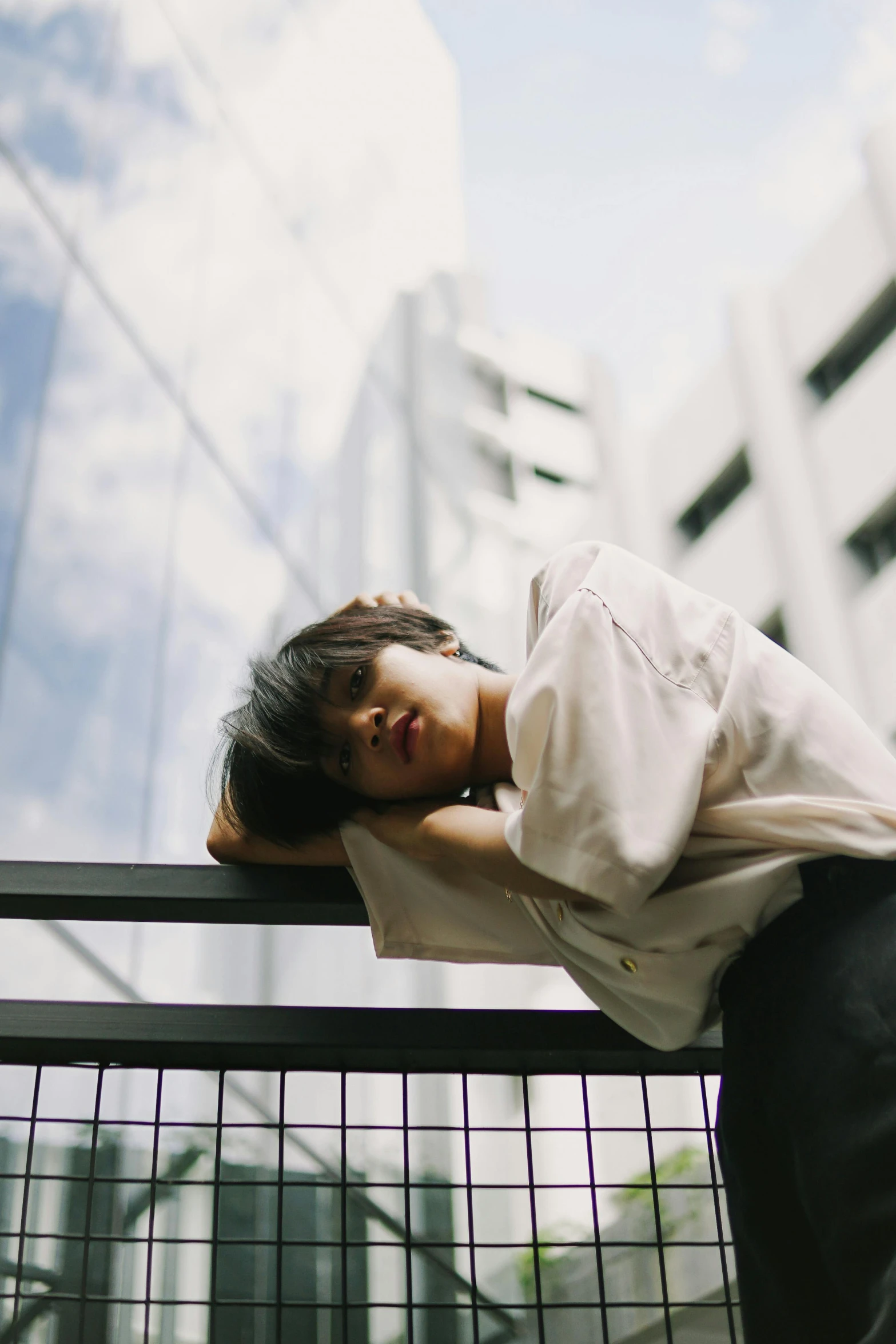 the woman is posing with her head on a railing