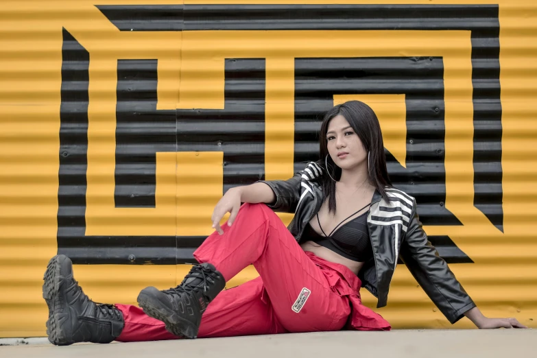 a young woman is sitting by a yellow wall