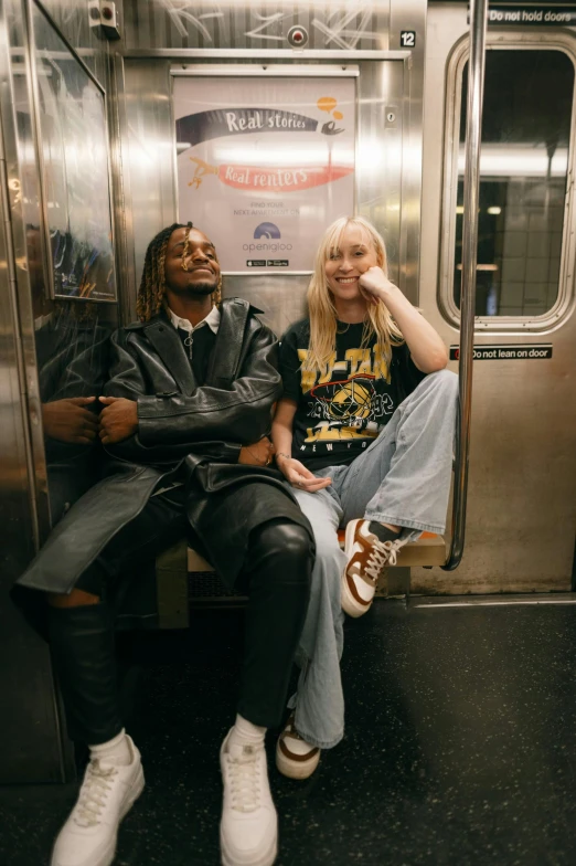 two people sitting on a subway bench on a subway