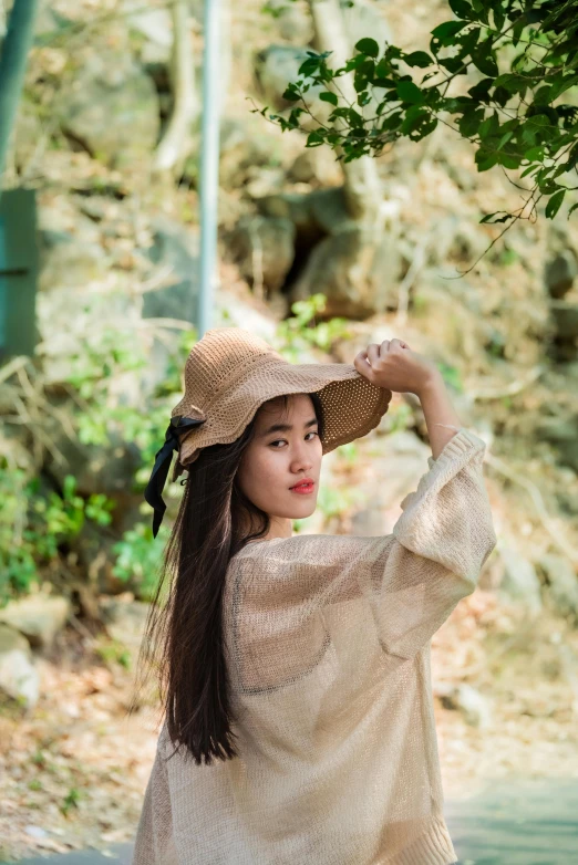 a woman standing next to a tree wearing a hat