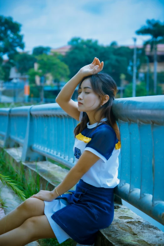 a woman sitting on a wooden bench in front of some blue railing