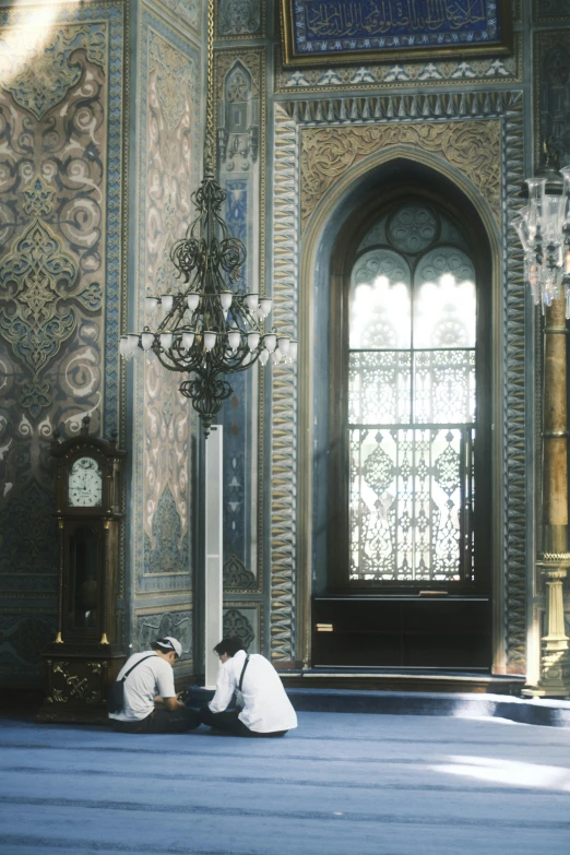 two men kneeling on the floor in a room with paintings on the wall