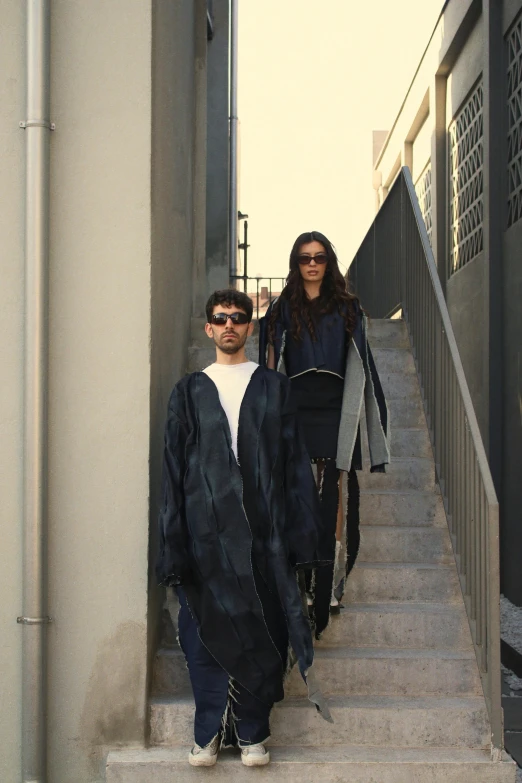 a man in sunglasses is standing on some stairs and next to a woman